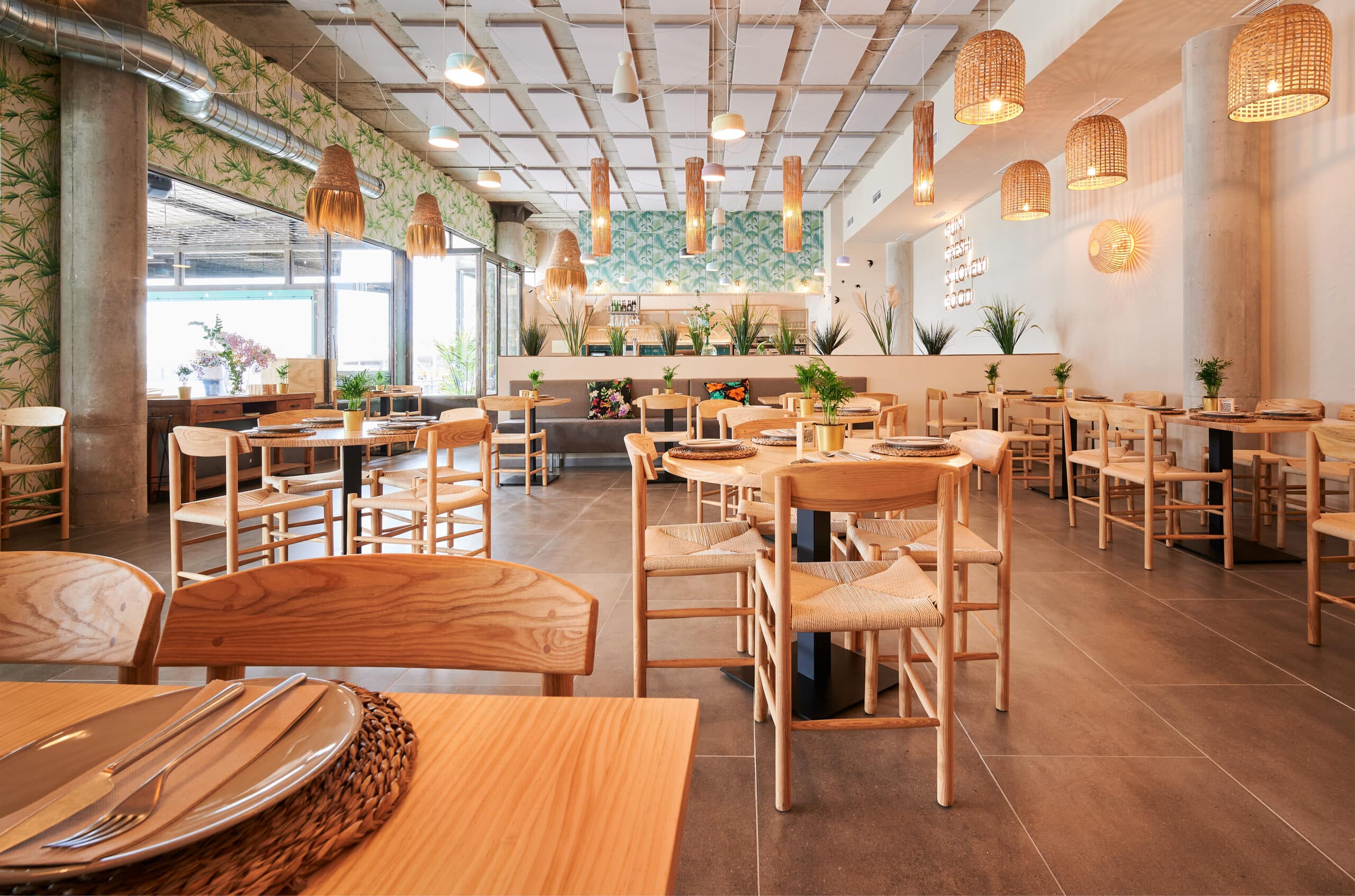 restaurant vide au design rustique avec des meubles en bois et quelques plantes décoratives et des panneaux acoustiques au plafond